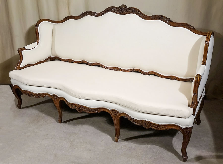 Grand canapé à joues Louis XV en noyer sculpté par Pierre Nogaret