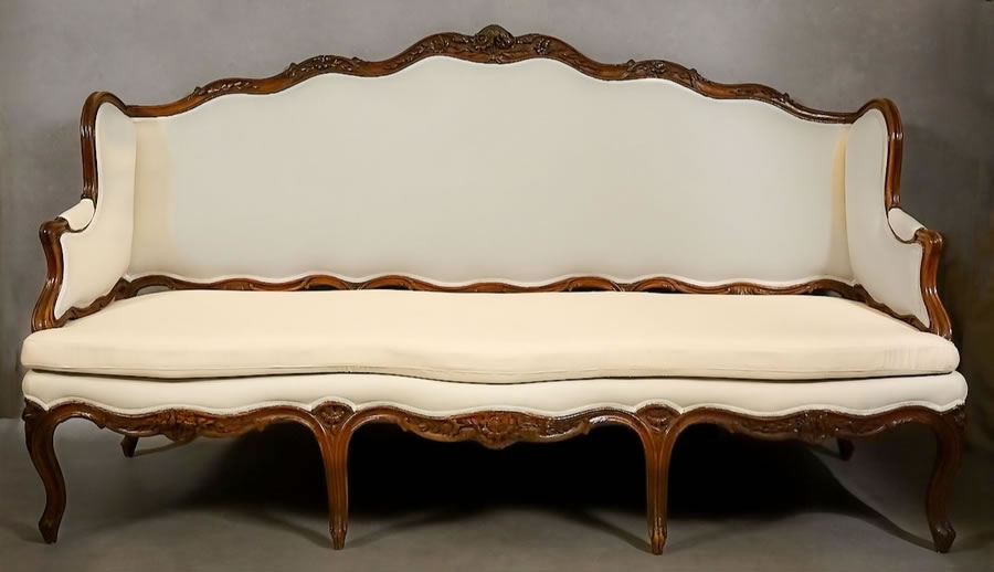 Grand canapé à joues estampillé Pierre Nogaret, en noyer sculpté, Lyon, époque Louis XV.
